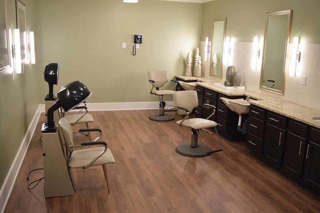 A well-lit salon with multiple styling chairs, mirrors, and hair dryers.
