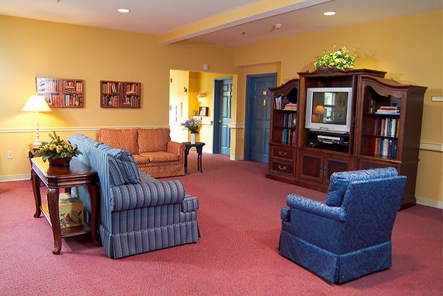 A cozy living room featuring comfortable sofas, armchairs, a television, and warm-colored walls.