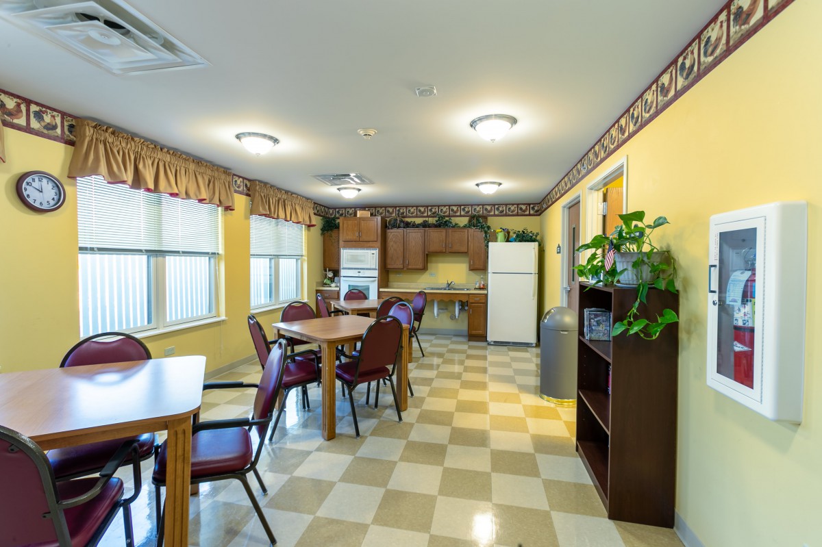 A spacious kitchen and dining area with wooden cabinets, a refrigerator, and checkered flooring.