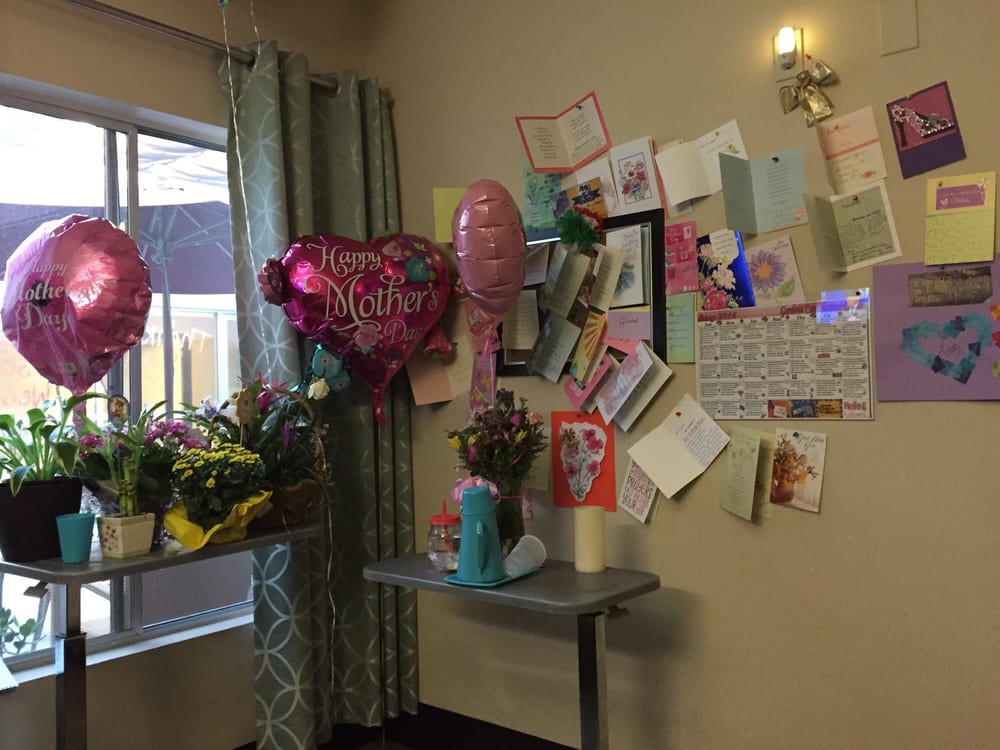 A room corner decorated with balloons, flowers, and cards, creating a festive atmosphere.