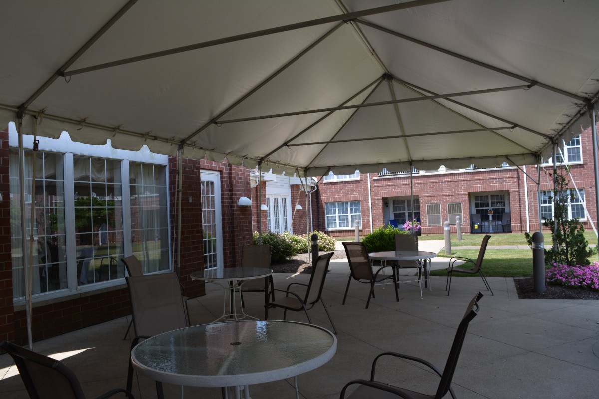A covered patio with tables and chairs outside a building.