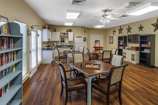A cozy dining area with tables and chairs, featuring a kitchenette and decorative elements.