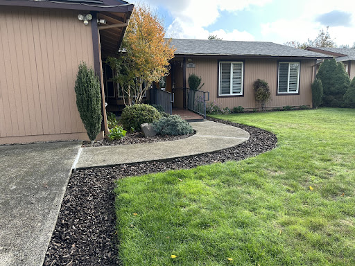 A beautifully landscaped front yard featuring a curved pathway and lush green lawn.