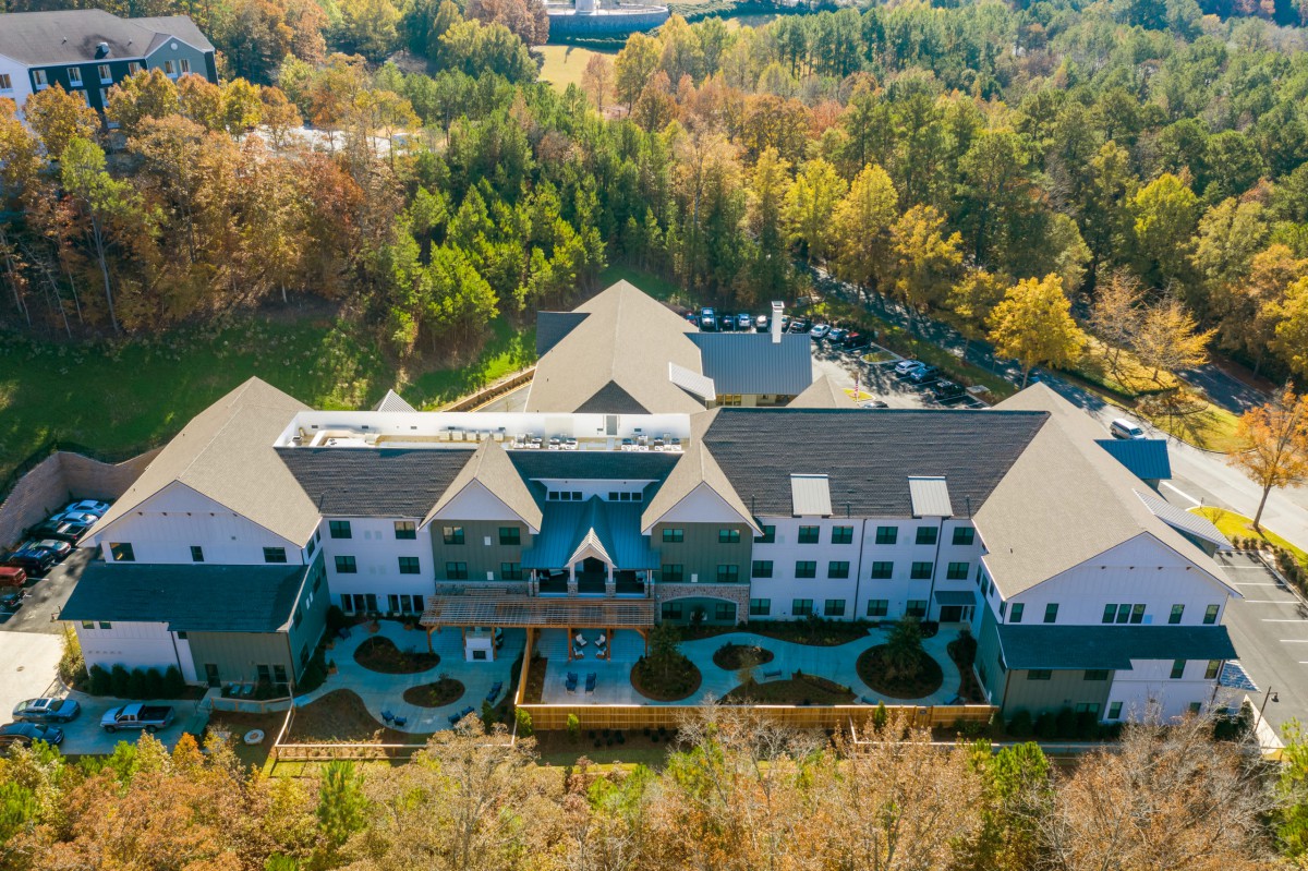 Aerial view of a large building surrounded by autumn trees and forest.