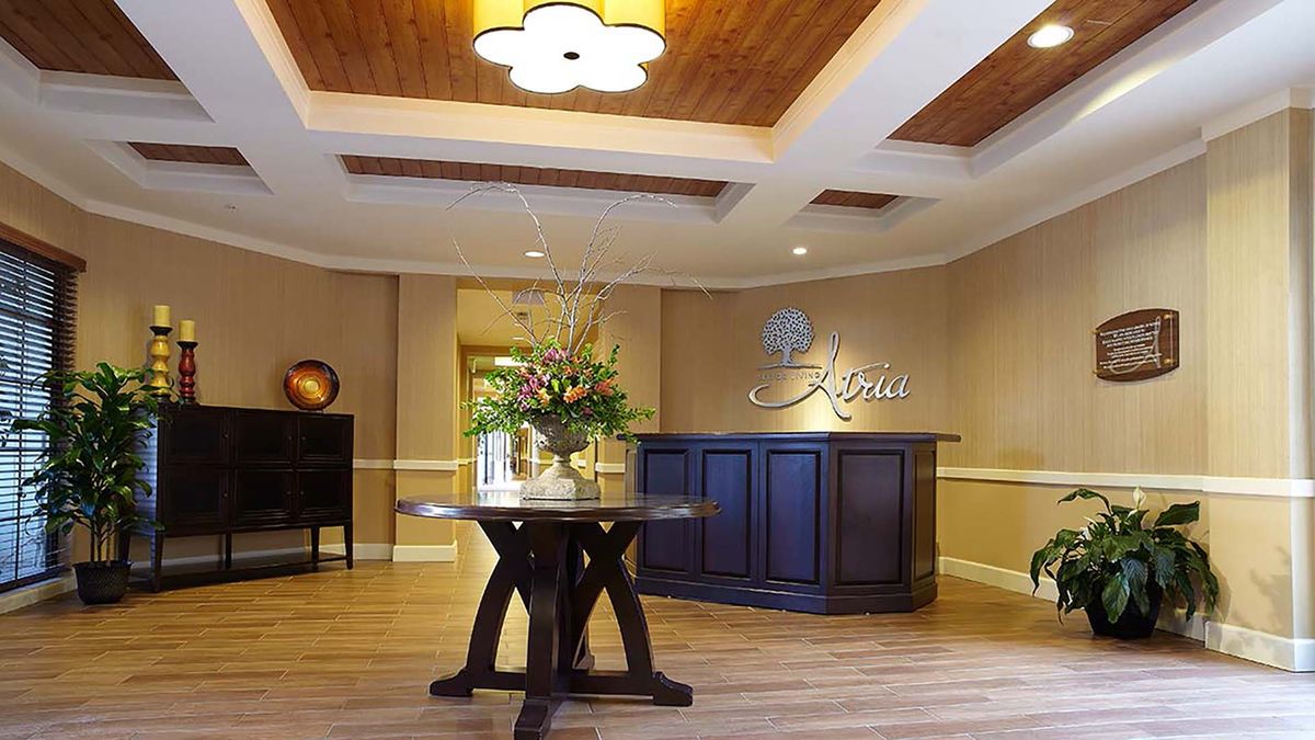 A welcoming reception area featuring elegant wood flooring and a decorative ceiling, complete with a floral centerpiece on a wooden table.