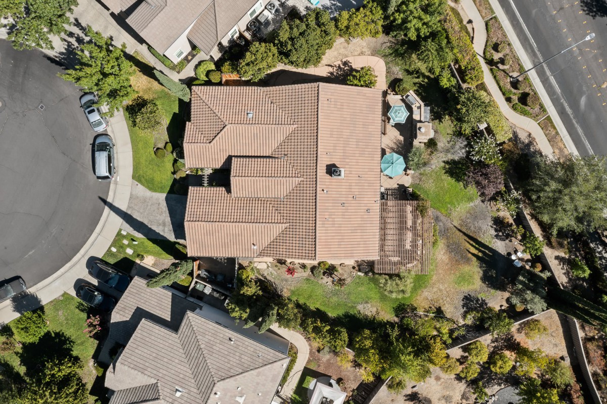Aerial view of a suburban house with a spacious backyard and surrounding greenery.
