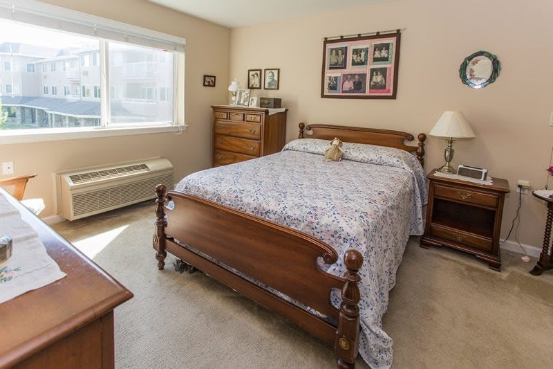 A cozy bedroom with wooden furniture and a large window.