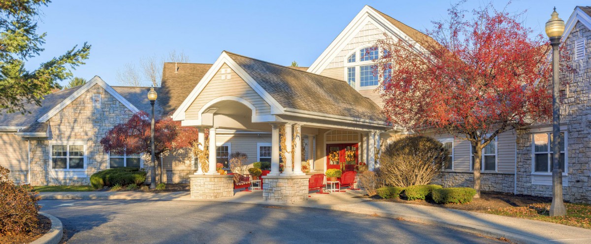 A welcoming entrance to a residential building surrounded by trees and landscaping.