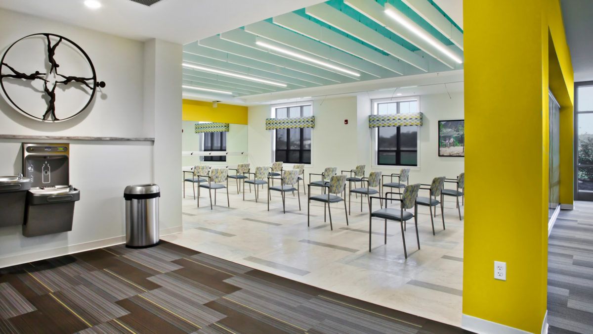 A modern, empty cafeteria with tables and chairs arranged neatly under bright lighting.