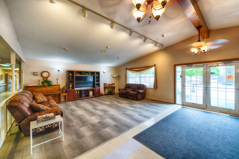 Spacious living room with cozy seating and a large television, featuring ample natural light.