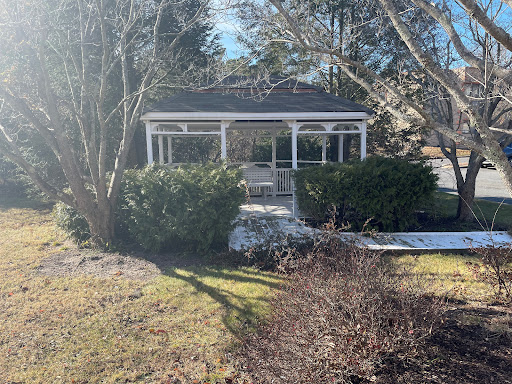 A charming gazebo surrounded by lush greenery, illuminated by sunlight.