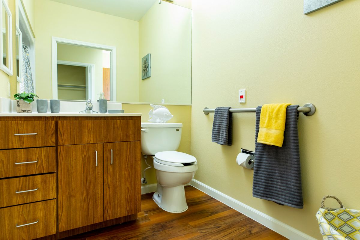 A clean and modern bathroom with a wooden cabinet, toilet, and towels.