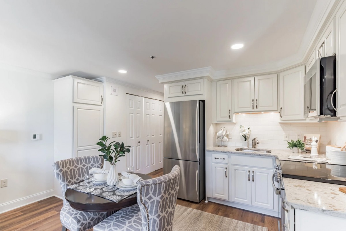 A modern kitchen and dining area with white cabinets and stainless steel appliances.