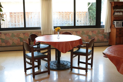 A cozy dining setup featuring a round table and four chairs, illuminated by natural light.