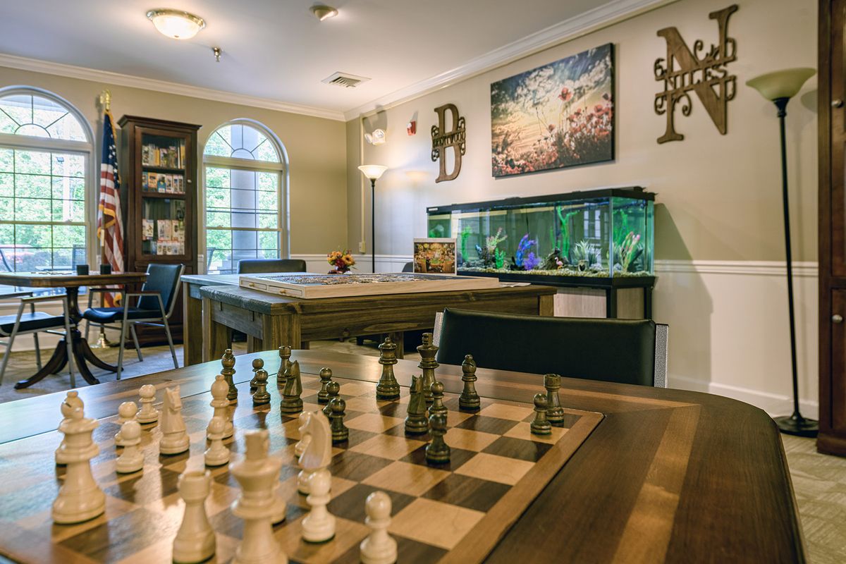 A cozy room featuring a chess board, fish tank, and decorative artwork.