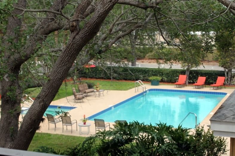 A serene outdoor pool surrounded by lush greenery and seating areas.
