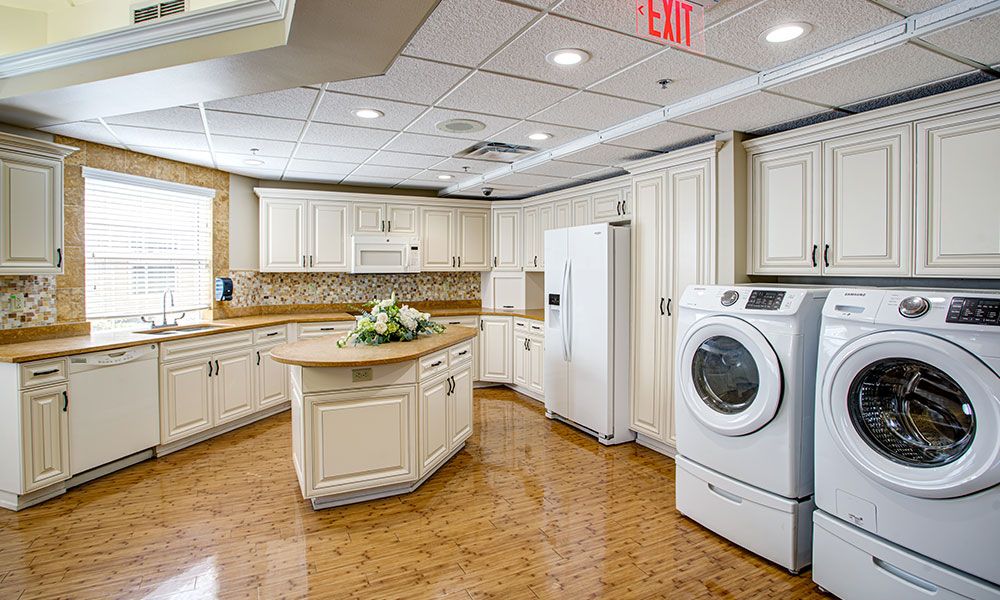 A modern kitchen with white cabinets, a center island, and a washer integrated into the space.