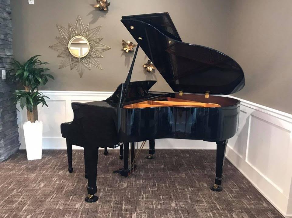 A grand piano displayed in a stylishly decorated room with a clock and plants.