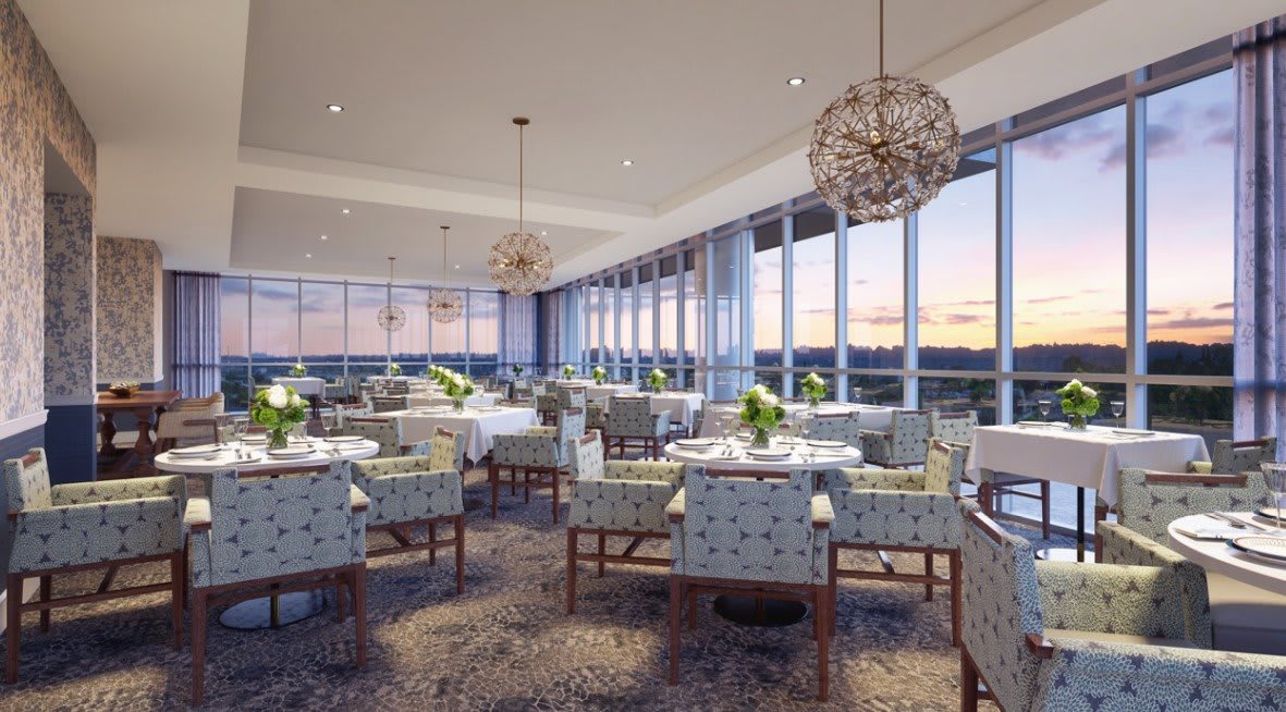A beautifully designed restaurant interior with elegant lighting and a scenic sunset view through large windows.