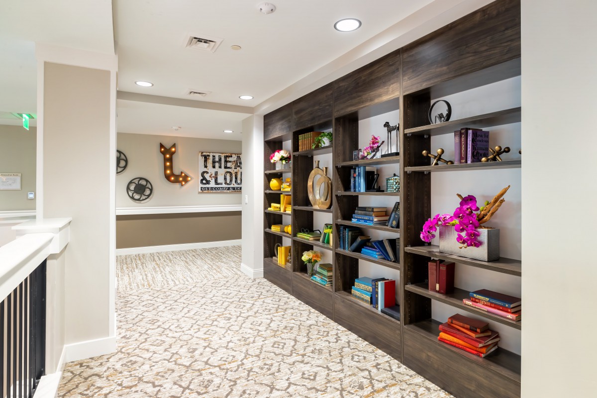 A modern hallway interior featuring a large bookshelf with various books and decorative items.