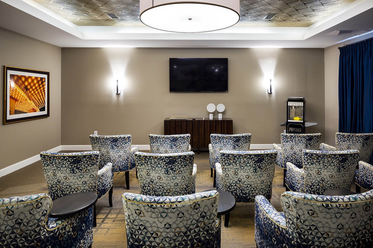 A modern conference room with patterned chairs, a television, and elegant lighting.