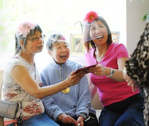 A group of women enjoying time together, wearing flower headbands and smiling indoors.