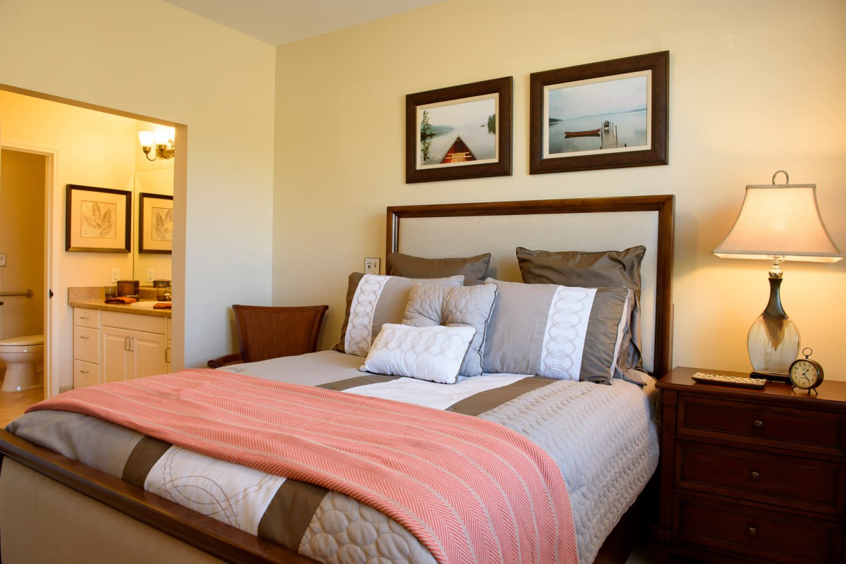 A cozy bedroom with a neatly made bed, adorned with decorative pillows and a warm blanket.
