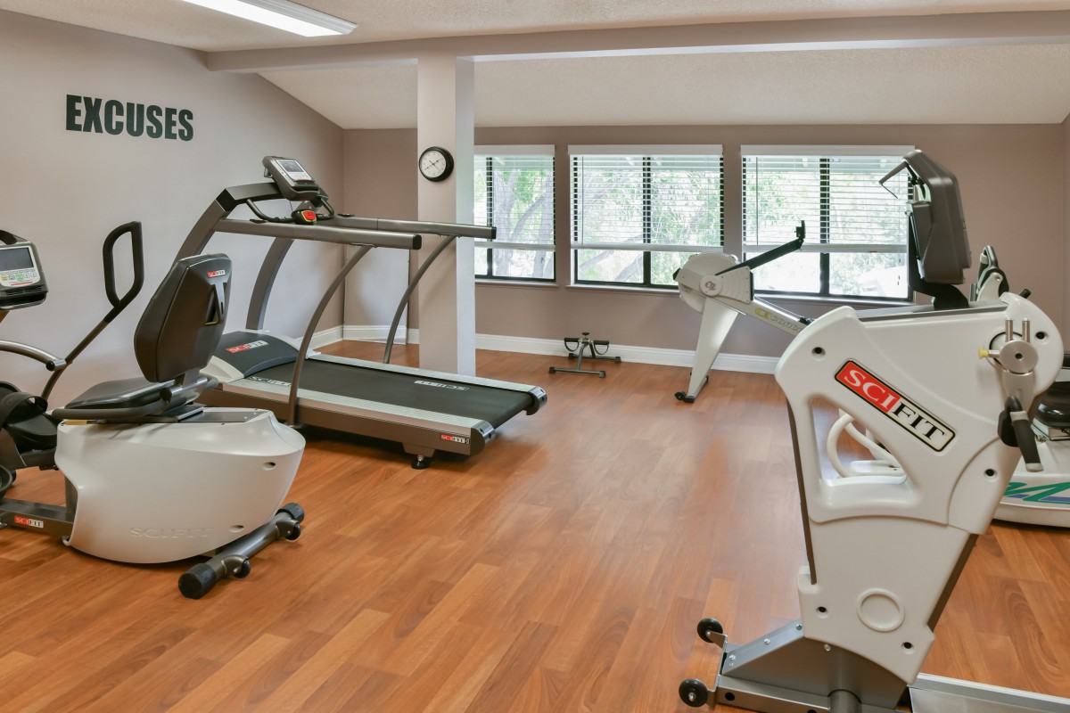 A modern gym with treadmills and an elliptical machine, featuring a bright and spacious workout area.