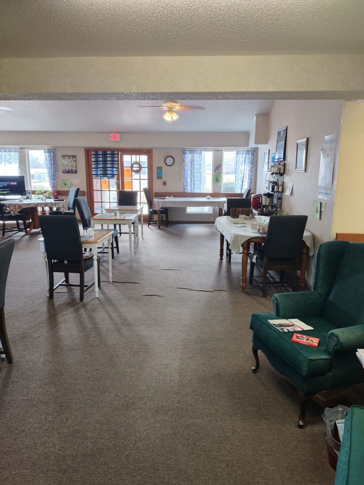 A spacious indoor living and dining area with chairs, tables, and carpeted flooring.