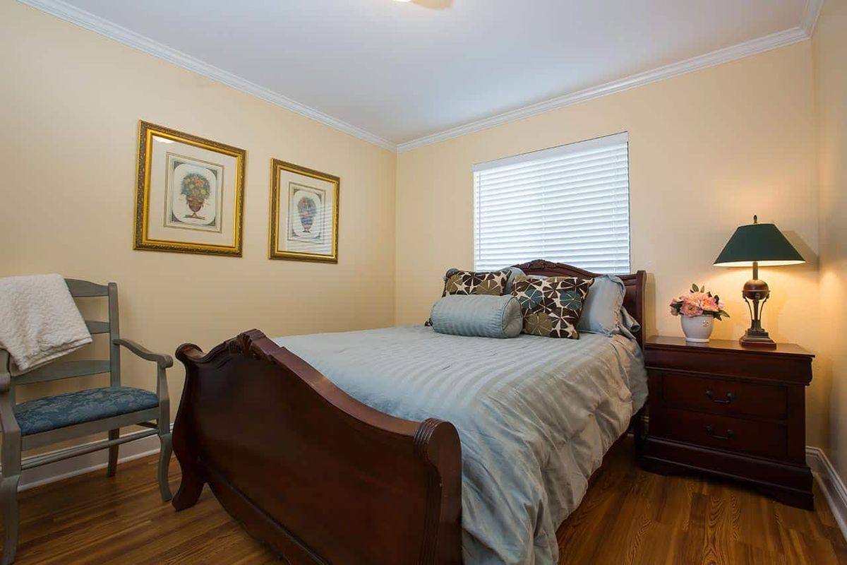 A cozy bedroom with a wooden bed, decorative pillows, and wall art.