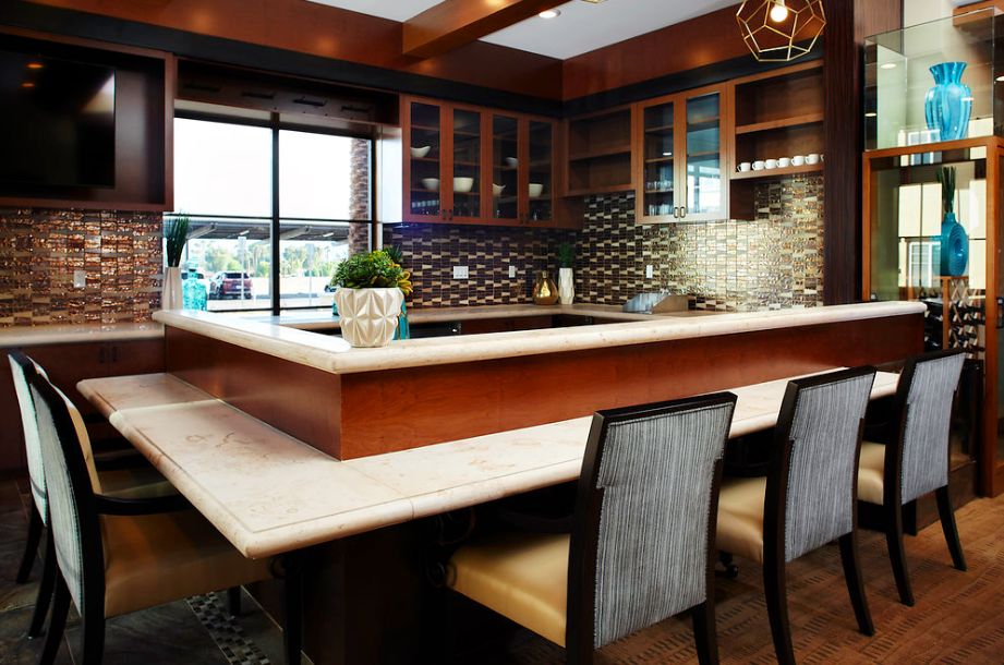 A modern kitchen with bar seating, featuring a tile backsplash and wood accents.