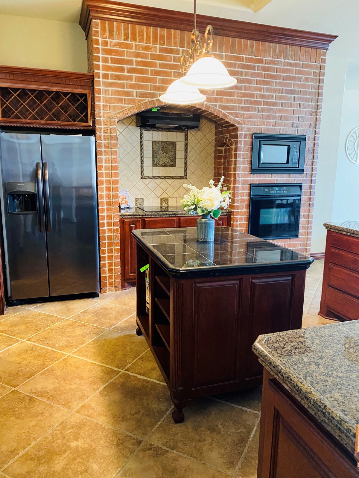 Modern kitchen with a central island, brick accents, and stainless steel appliances.