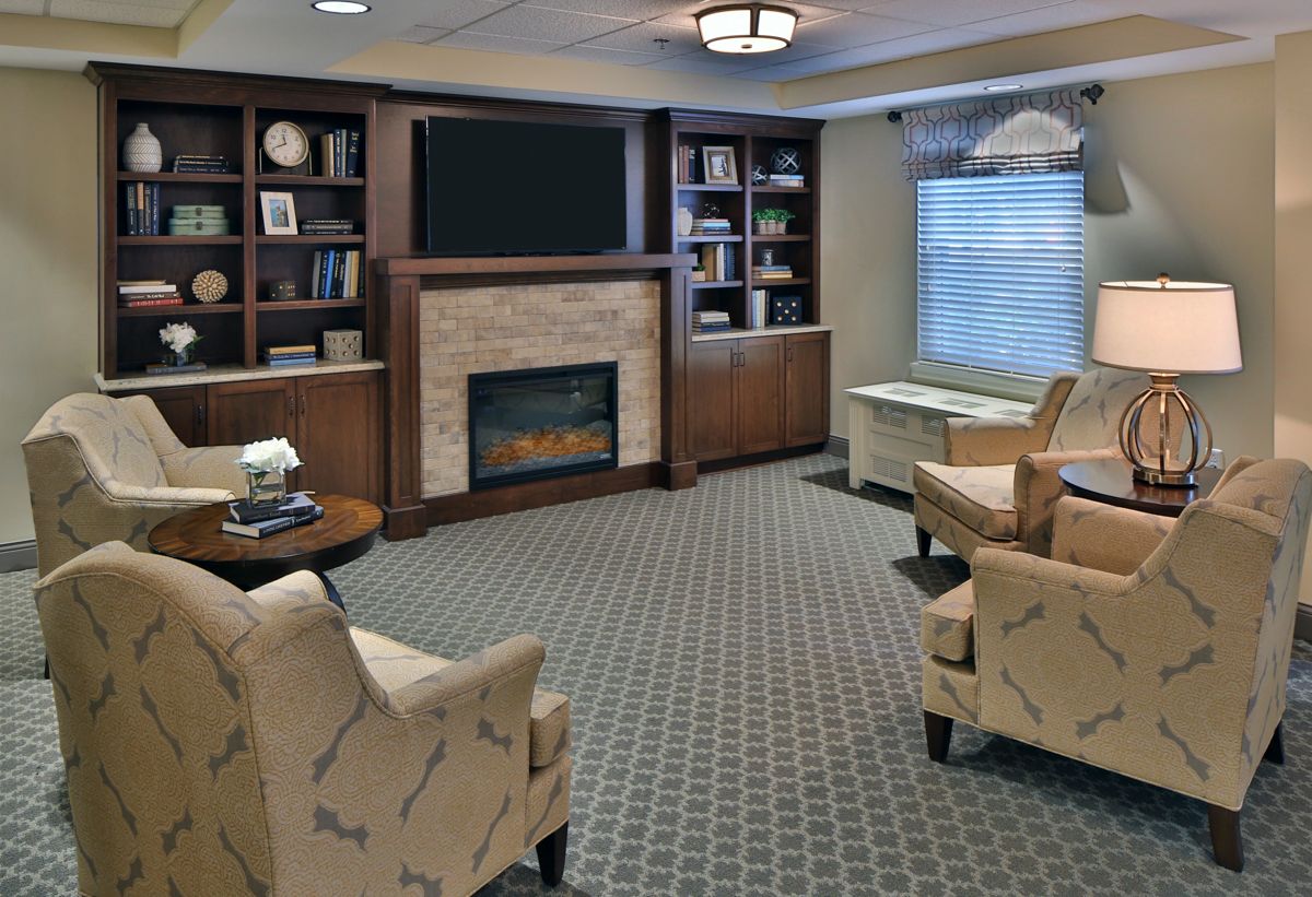 A cozy living room with a fireplace, bookshelves, and comfortable seating.