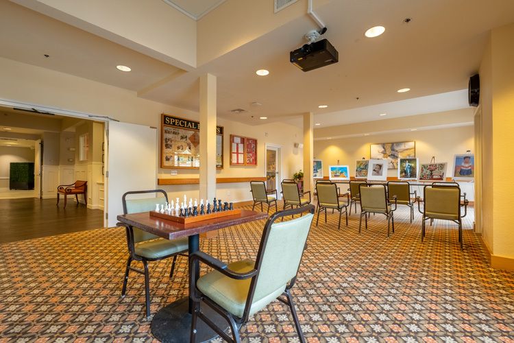 A well-lit game room with a chessboard set up on a table, surrounded by chairs, offering a comfortable space for recreational activities.
