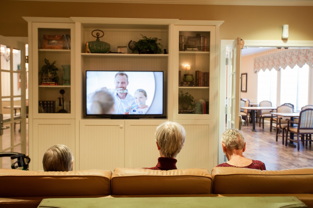 Three people sitting on a couch watching television in a cozy living room.
