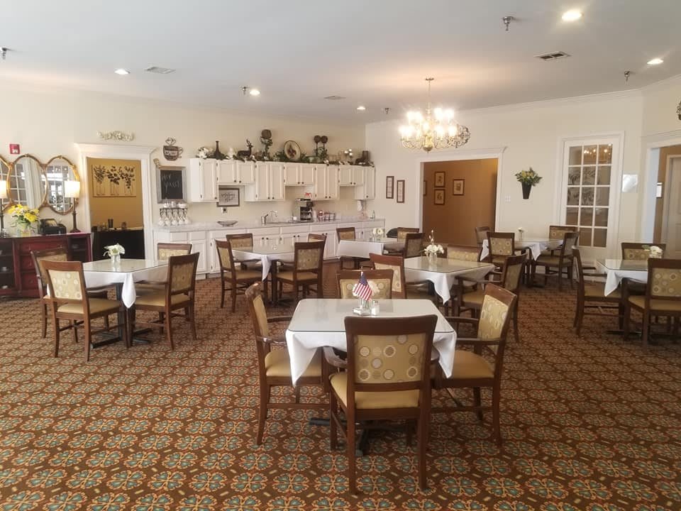 A spacious dining room with neatly arranged tables and chairs, featuring elegant decor and a warm, inviting atmosphere.