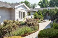 A quaint house with well-maintained landscaping and a variety of plants lining the pathway.