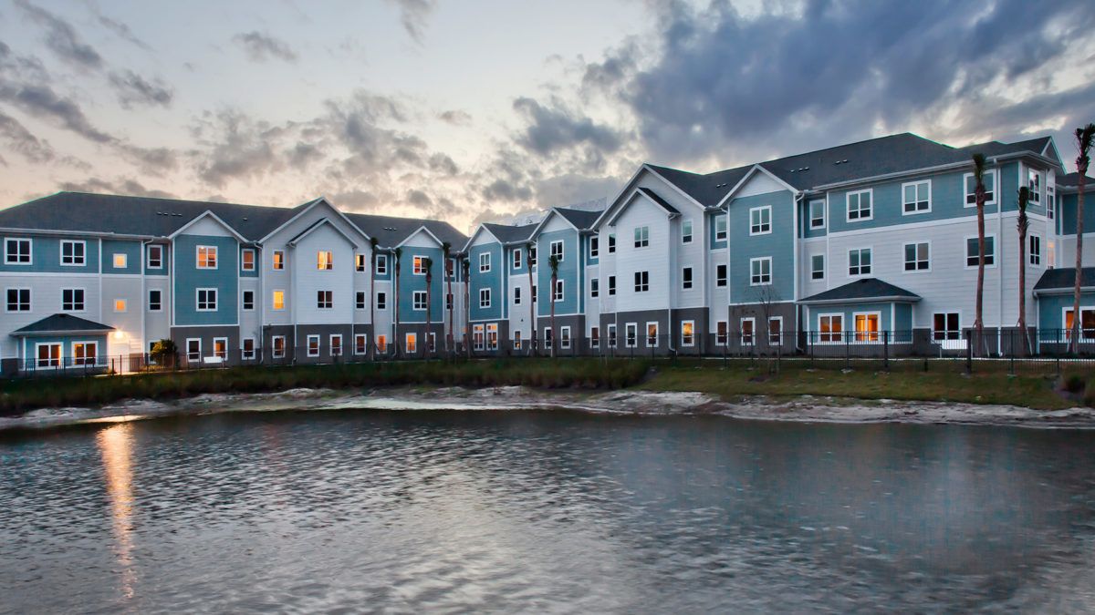 A row of waterfront residential buildings under a cloudy sky.