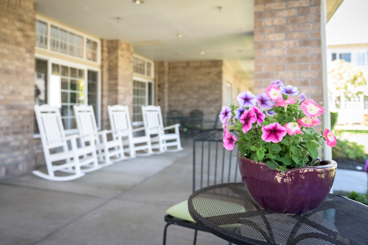 A cozy patio with rocking chairs and a table adorned with colorful flowers.
