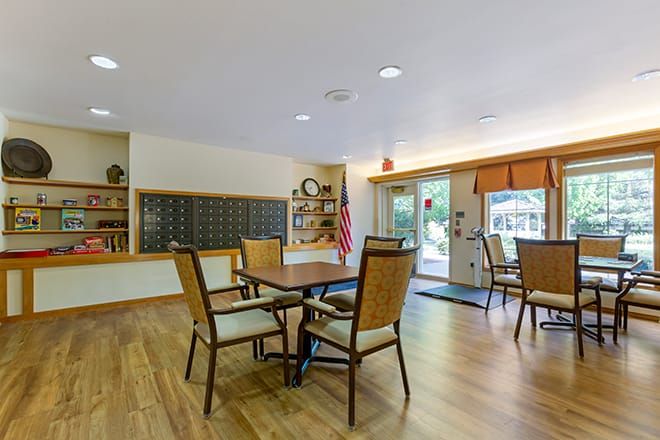 A well-lit lobby area featuring tables and chairs on a wooden floor.