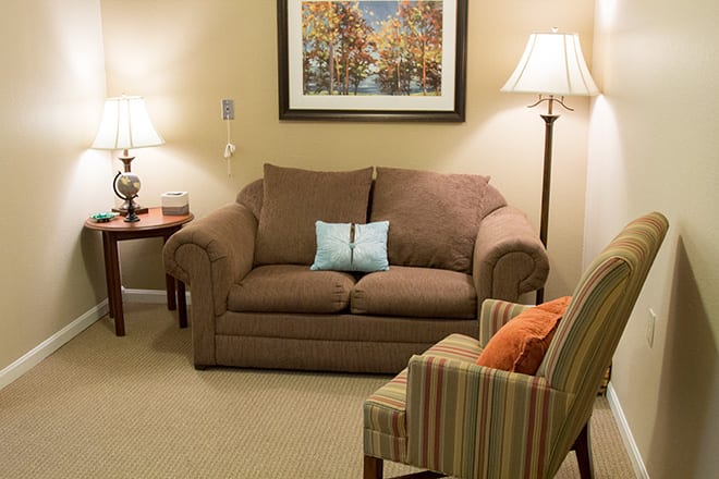 A cozy living room with a brown sofa, armchair, and warm lighting.