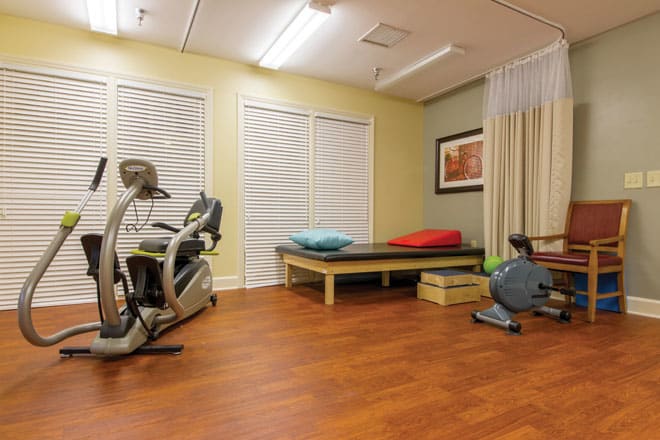 A well-equipped exercise and therapy room with fitness machines and a comfortable resting area.