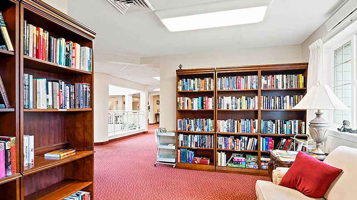 A cozy library with wooden bookshelves filled with books and a well-lit reading area.