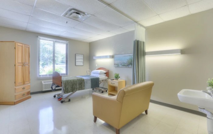 A clean and modern hospital room with a bed and seating area.