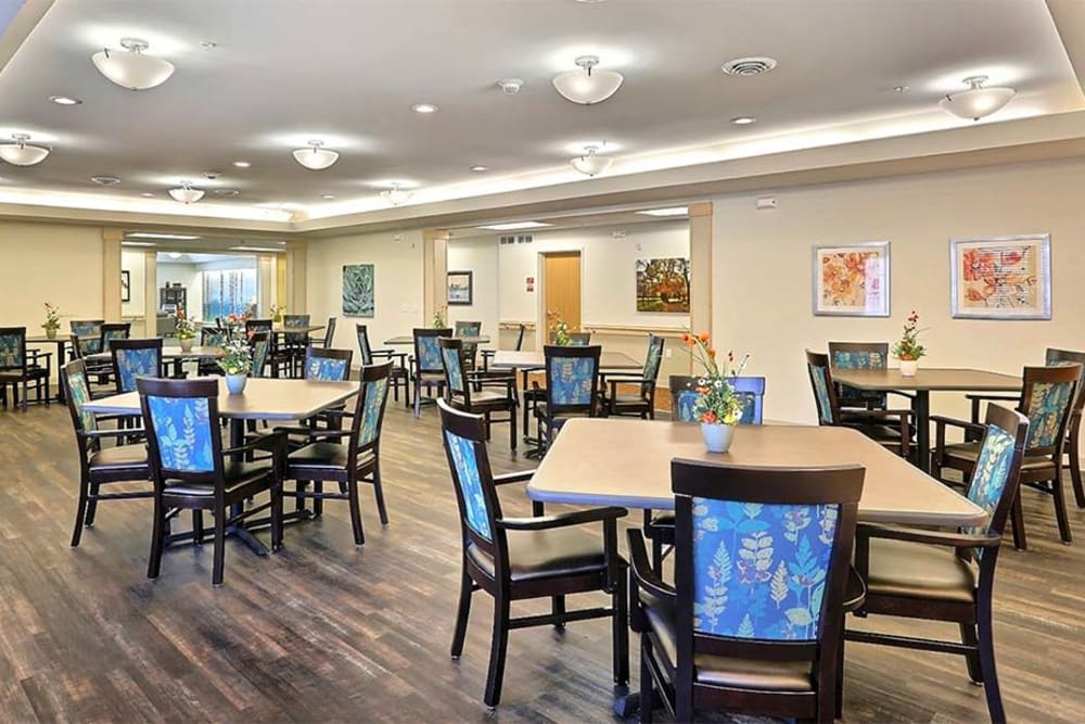 A spacious dining area with neatly arranged tables and chairs, featuring elegant lighting and wooden flooring.