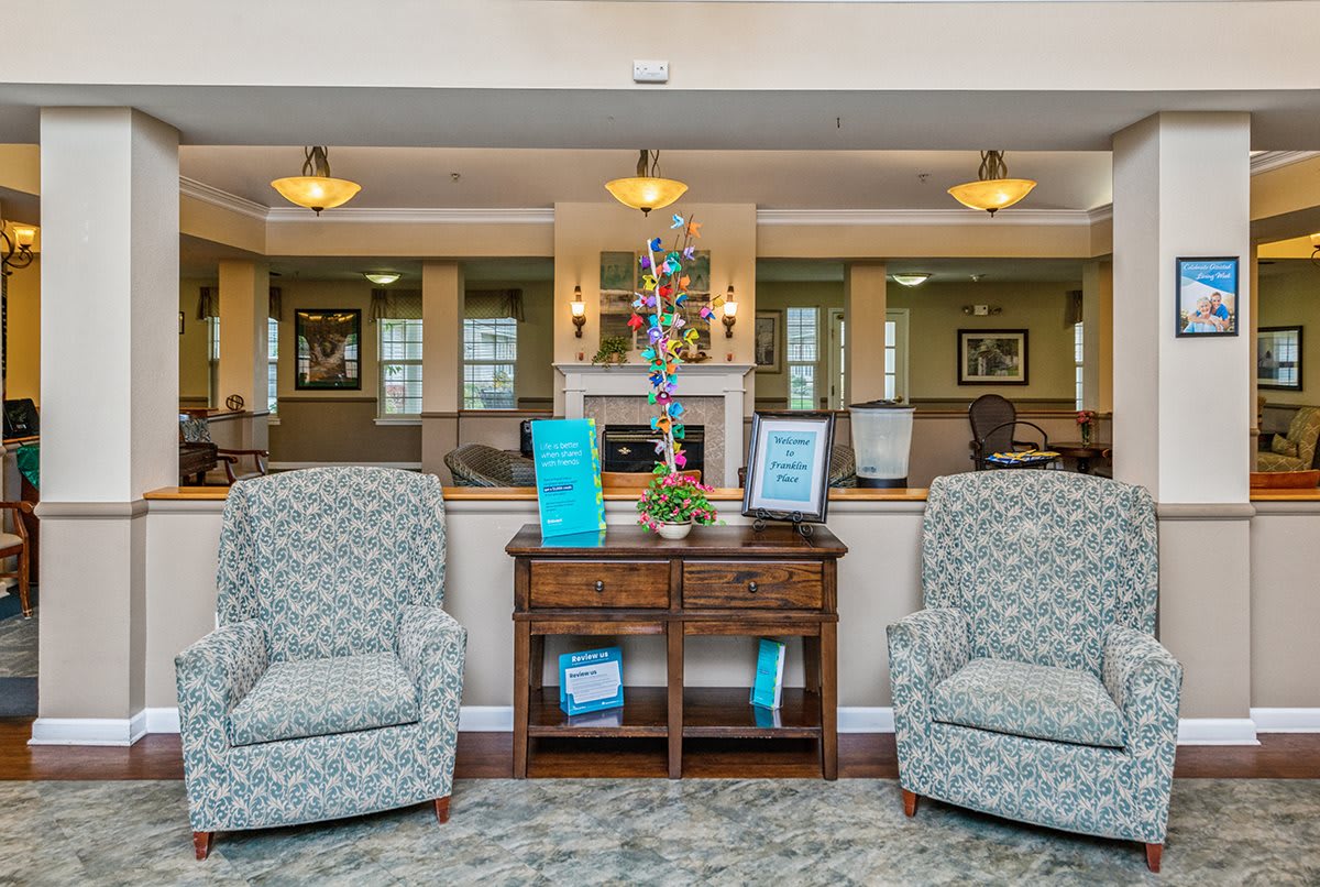 A comfortable lobby seating area with two patterned armchairs and a wooden table, adorned with decor and soft lighting.