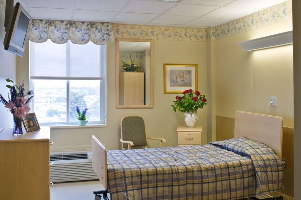 A clean and well-organized hospital room with a single bed and floral decor.