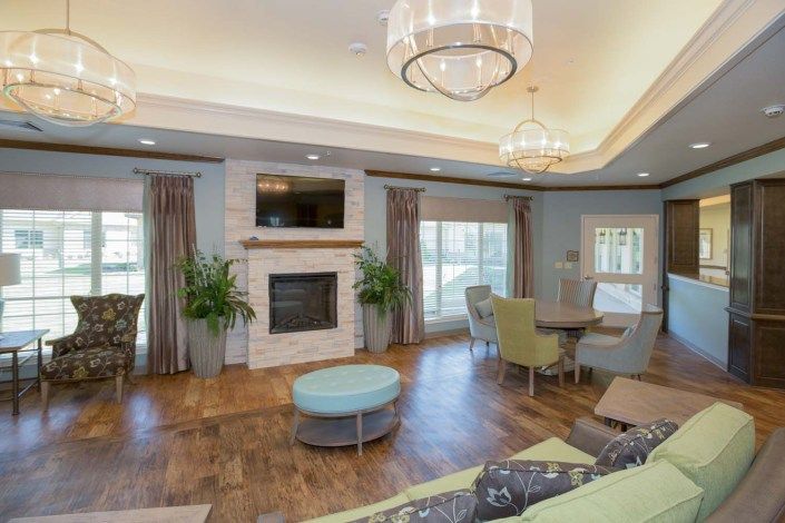A modern living room with a fireplace and elegant chandelier, featuring wood flooring and stylish furnishings.