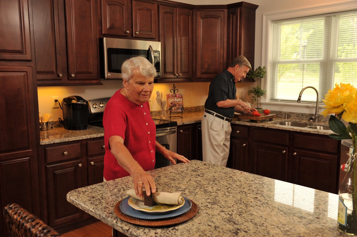 An elderly couple preparing food together in a cozy kitchen setting.