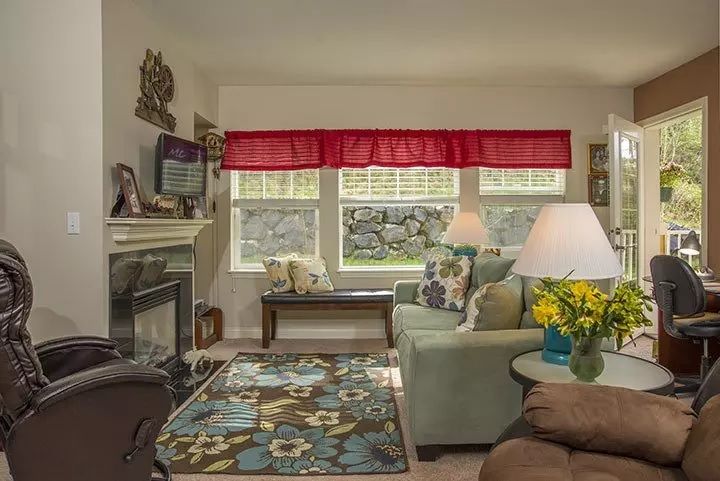 Cozy living room with a fireplace, decorated with a floral rug and colorful accents.